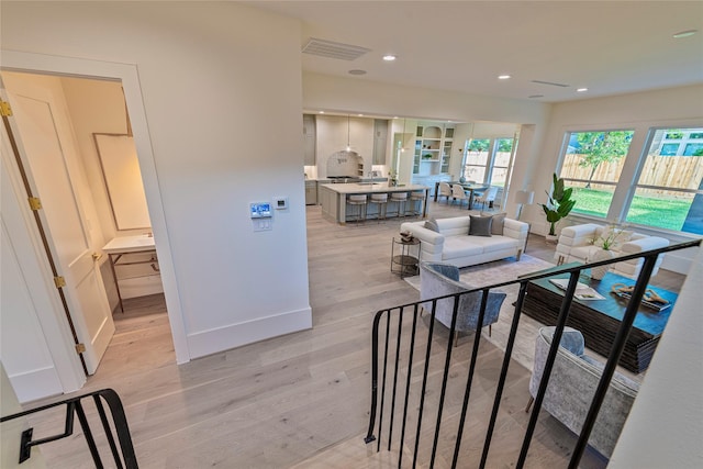 living area with baseboards, light wood-style floors, visible vents, and recessed lighting
