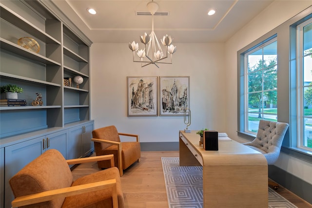 office with light wood-type flooring, baseboards, visible vents, an inviting chandelier, and a raised ceiling