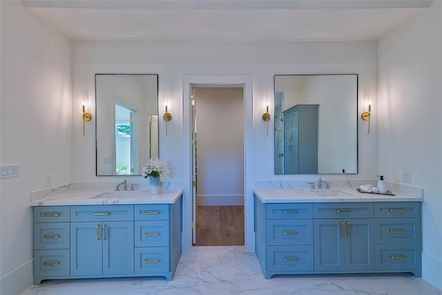 full bath featuring marble finish floor, two vanities, and a sink