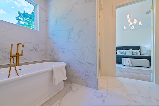 bathroom featuring tile walls, marble finish floor, an inviting chandelier, a soaking tub, and ensuite bath
