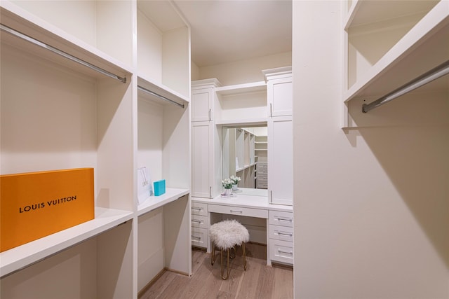 spacious closet with built in study area and light wood finished floors
