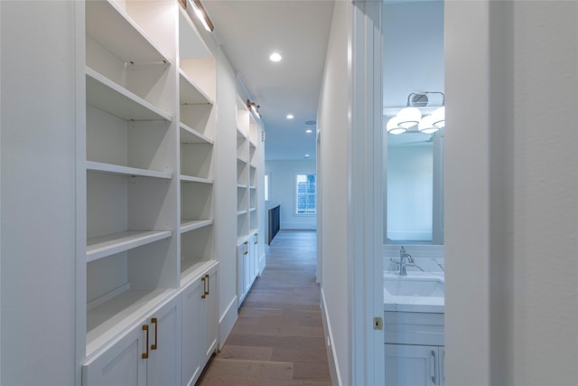 corridor with recessed lighting, dark wood finished floors, baseboards, and a sink