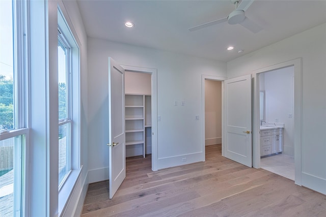unfurnished bedroom with a spacious closet, baseboards, recessed lighting, and light wood-type flooring