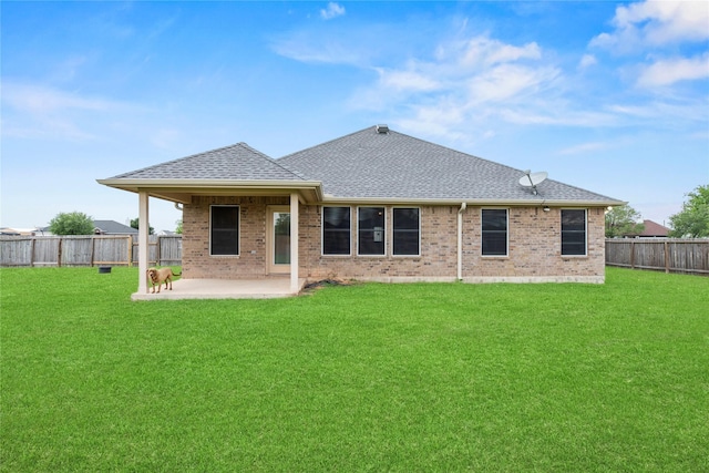 back of property with brick siding, a lawn, a fenced backyard, and a patio