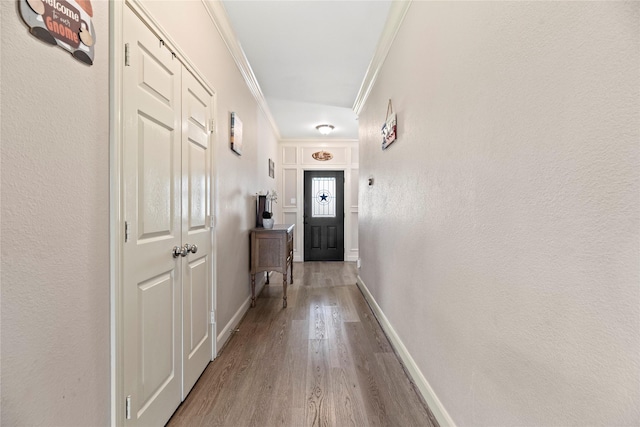 corridor featuring baseboards, wood finished floors, and crown molding