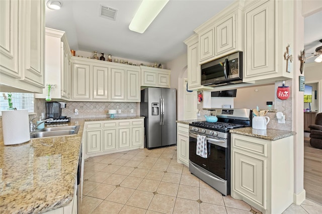 kitchen with stainless steel appliances, backsplash, visible vents, a sink, and cream cabinets