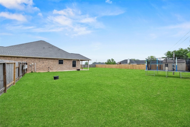 view of yard with a trampoline and a fenced backyard