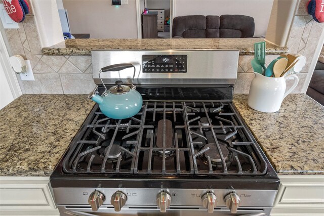 details featuring backsplash, stone countertops, and gas range