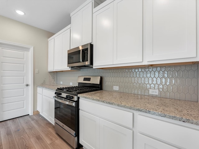 kitchen with light wood-style flooring, white cabinetry, and appliances with stainless steel finishes