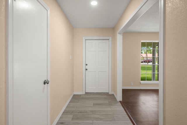 corridor with light wood finished floors and baseboards