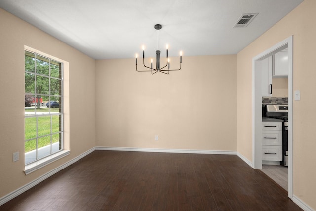 unfurnished dining area with dark wood finished floors, an inviting chandelier, visible vents, and baseboards