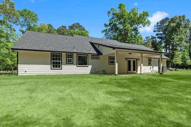 rear view of house featuring roof with shingles, a yard, and french doors