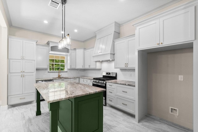 kitchen featuring stainless steel appliances, a center island, a sink, visible vents, and premium range hood