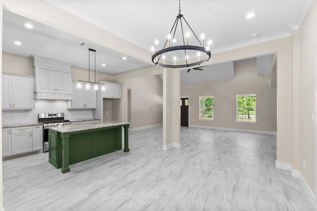 kitchen featuring crown molding, baseboards, stainless steel gas range, and open floor plan