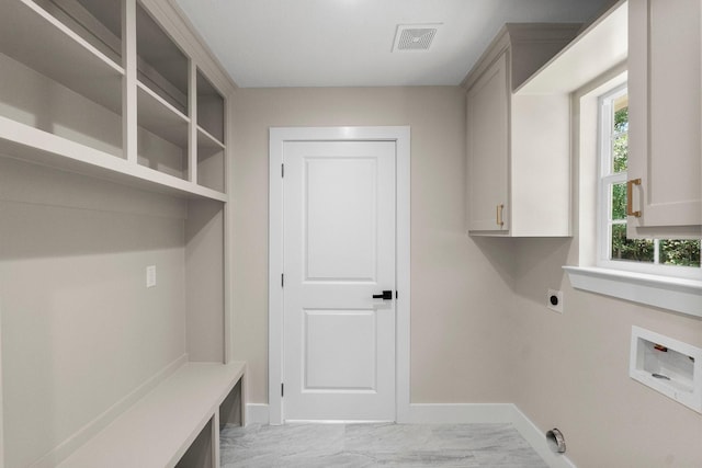 washroom featuring electric dryer hookup, baseboards, visible vents, and cabinet space