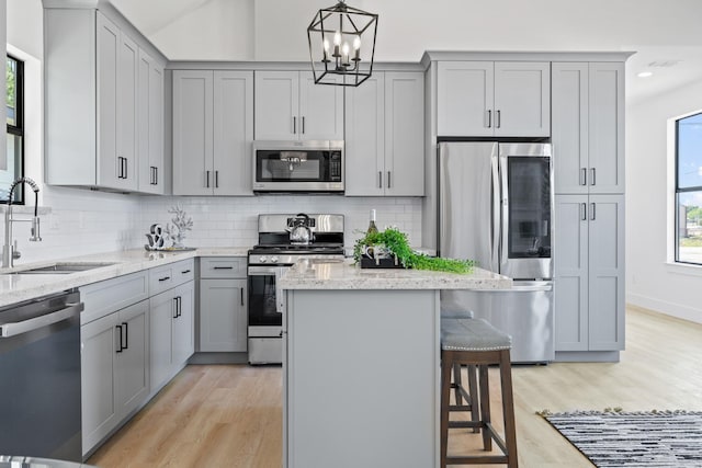 kitchen featuring stainless steel appliances, a sink, and gray cabinets
