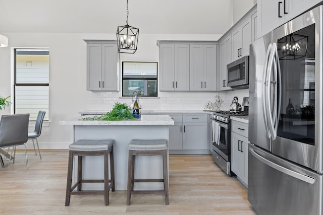 kitchen featuring appliances with stainless steel finishes, gray cabinets, and an inviting chandelier