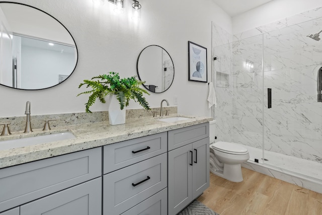 full bath with toilet, wood finished floors, a sink, and a marble finish shower
