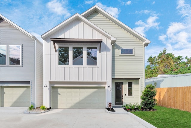 view of front of house with concrete driveway, fence, board and batten siding, and a garage