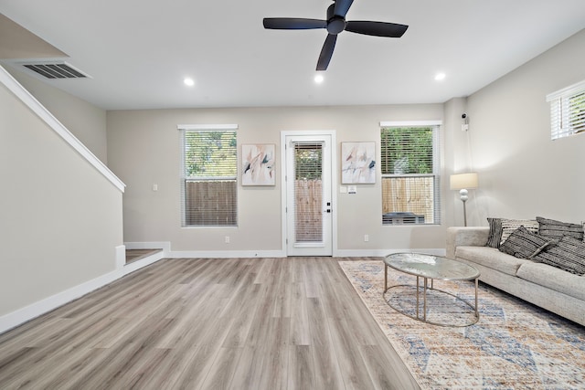 living area featuring plenty of natural light, ceiling fan, visible vents, and light wood-style flooring