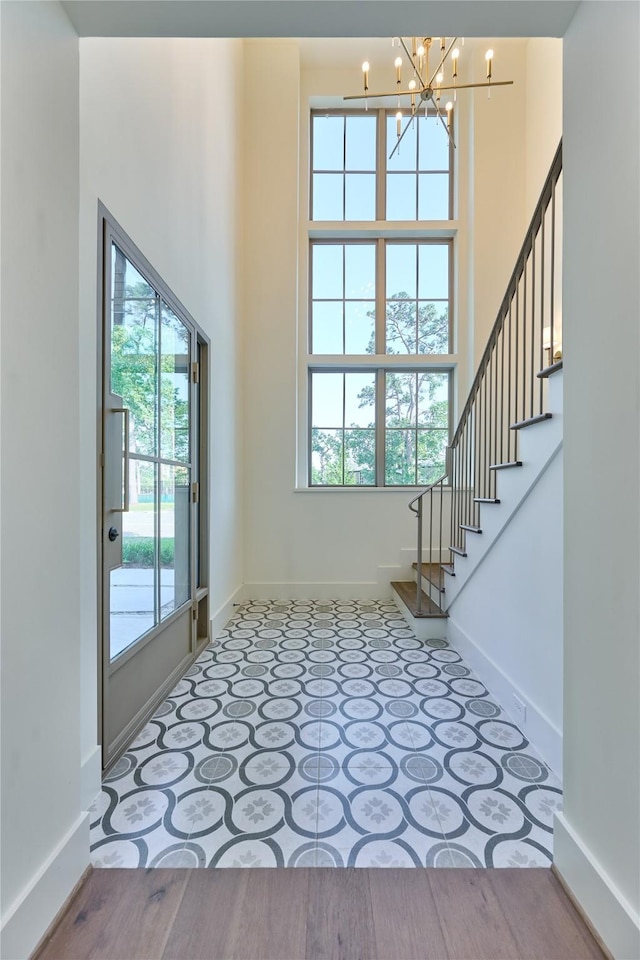 entrance foyer featuring stairs, a notable chandelier, and baseboards