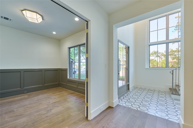 entryway featuring visible vents, light wood-type flooring, wainscoting, and recessed lighting
