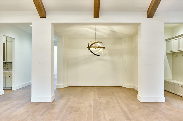 unfurnished dining area featuring light wood finished floors, beam ceiling, a chandelier, and baseboards