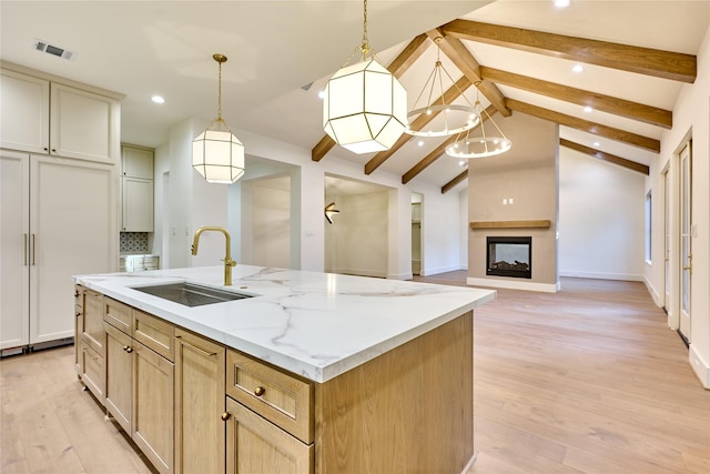 kitchen with light wood-style flooring, a sink, recessed lighting, a center island with sink, and vaulted ceiling with beams