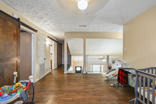 1858 Wood Orchard Dr, Missouri City, TX 77489 - hallway with wood finished floors, a barn door, visible vents, and a textured ceiling