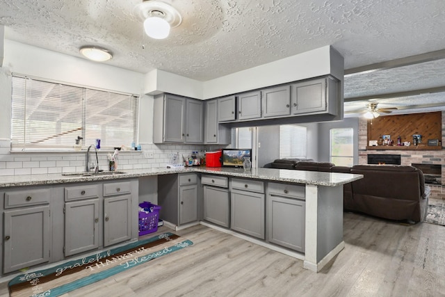1858 Wood Orchard Dr, Missouri City, TX 77489 - kitchen featuring gray cabinetry, a sink, a peninsula, and light wood-style floors
