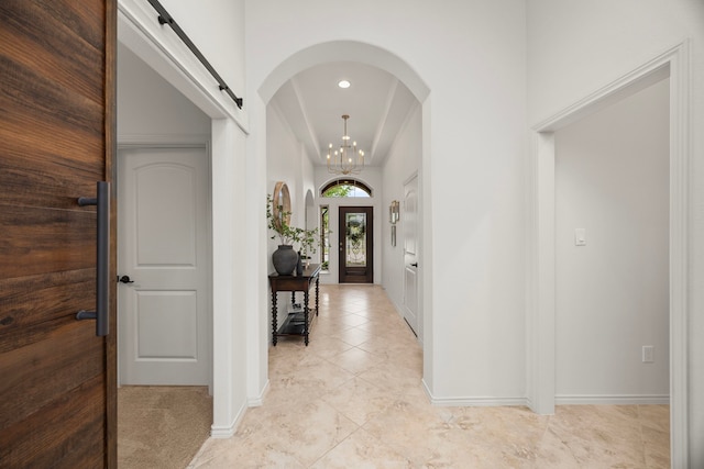 29119 Marina Point Ln, Fulshear, TX 77441 - foyer featuring light tile patterned floors, a barn door, baseboards, a chandelier, and arched walkways