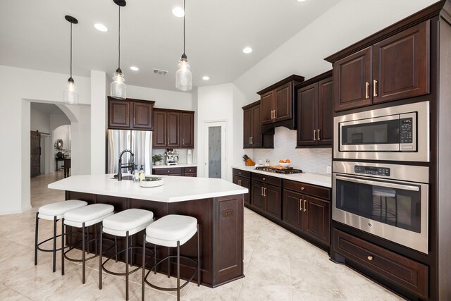 29119 Marina Point Ln, Fulshear, TX 77441 - kitchen with stainless steel appliances, light countertops, a sink, decorative backsplash, and a kitchen bar