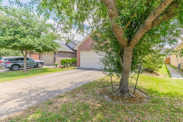 view of property hidden behind natural elements featuring brick siding, an attached garage, a front yard, and concrete driveway