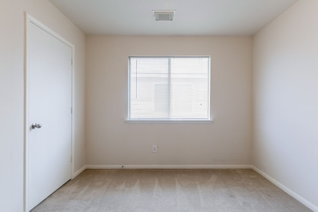 spare room with baseboards, visible vents, and light colored carpet