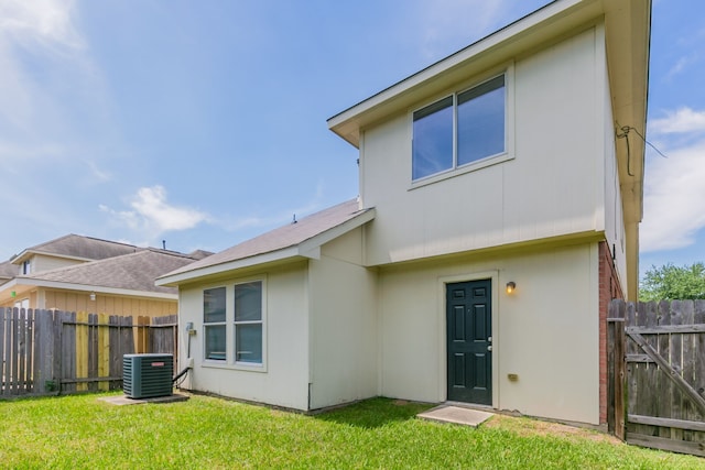 back of house featuring fence, a yard, central AC, and stucco siding