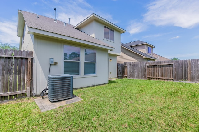 back of property featuring a lawn, a fenced backyard, and central AC unit