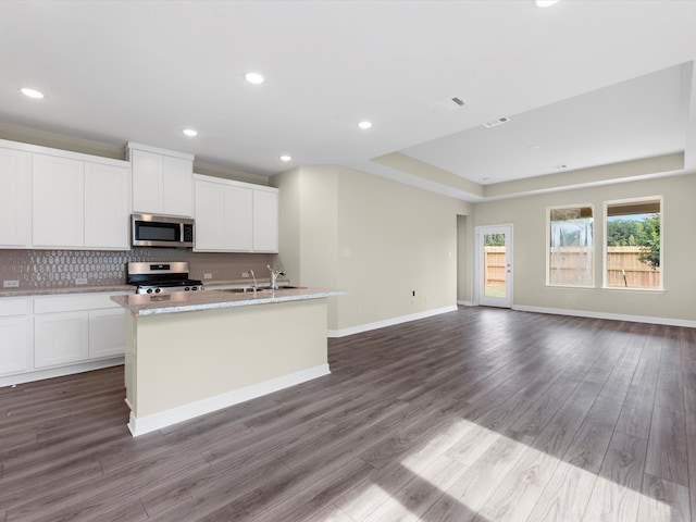 21719 White Bellflower Ln, Cypress, TX 77433 - kitchen featuring an island with sink, stainless steel appliances, backsplash, white cabinetry, and visible vents