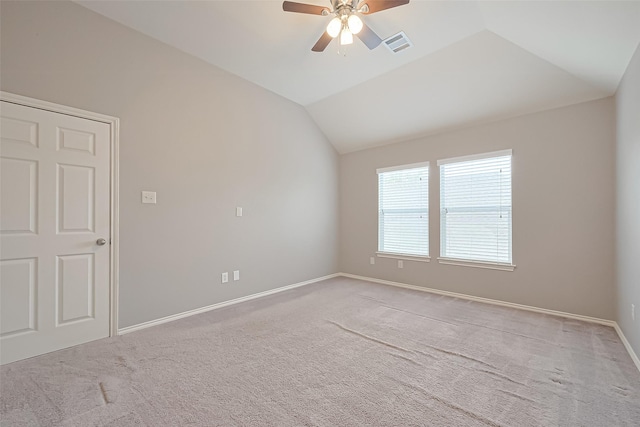 spare room with vaulted ceiling, visible vents, a ceiling fan, and carpet
