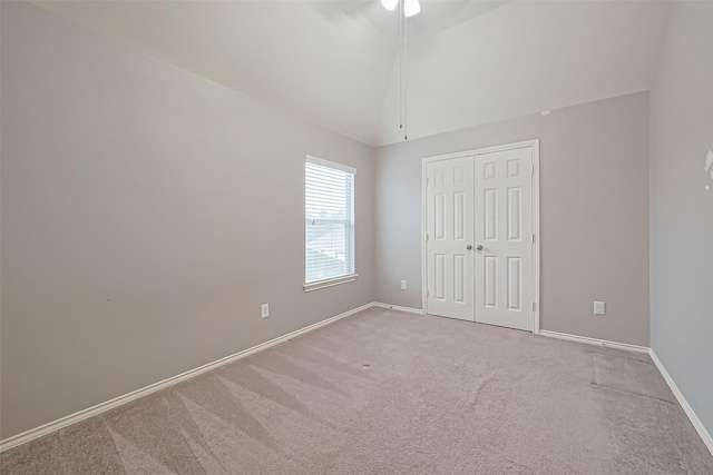 unfurnished bedroom featuring high vaulted ceiling, a closet, ceiling fan, baseboards, and carpet flooring