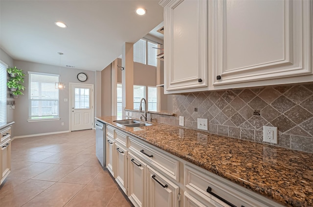 kitchen with tasteful backsplash, a sink, light tile patterned flooring, dishwasher, and baseboards