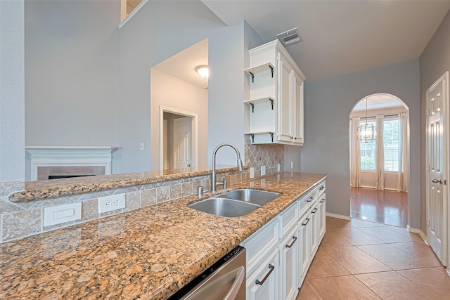 kitchen featuring light stone countertops, visible vents, white cabinetry, and a sink