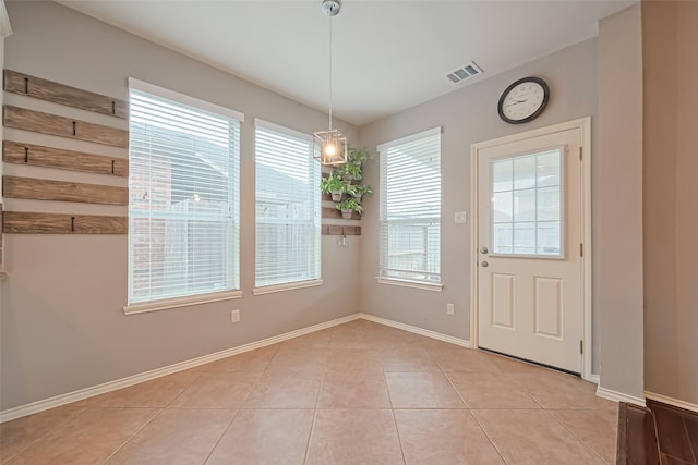 unfurnished dining area featuring baseboards, visible vents, and light tile patterned floors