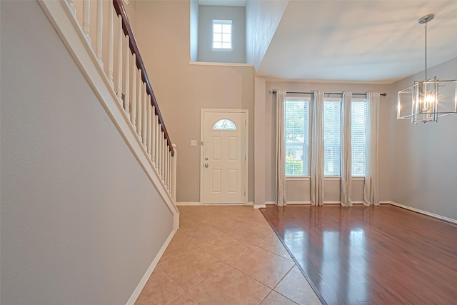 foyer with stairway, light tile patterned floors, an inviting chandelier, and baseboards