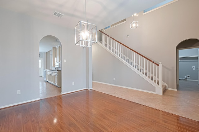 interior space with stairs, a sink, arched walkways, an inviting chandelier, and visible vents