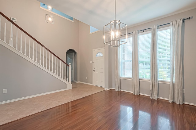 foyer entrance with arched walkways, baseboards, an inviting chandelier, wood finished floors, and stairway