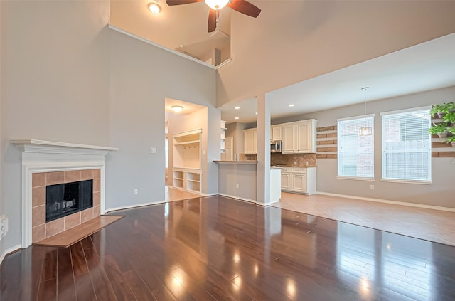 unfurnished living room featuring a ceiling fan, a tile fireplace, and light wood-type flooring