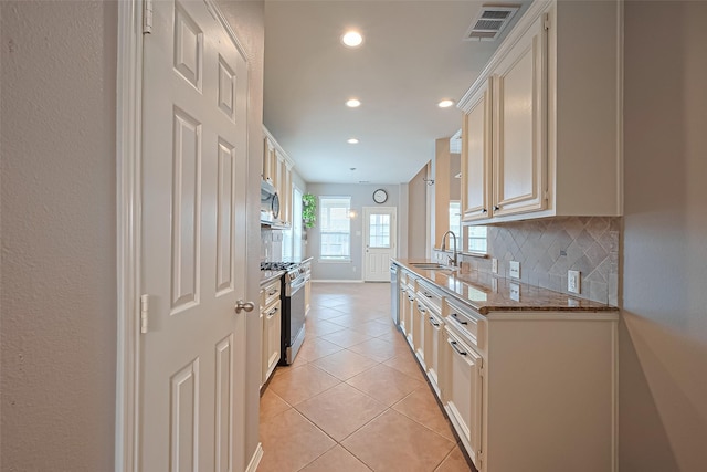 kitchen with a sink, light tile patterned floors, stainless steel appliances, backsplash, and visible vents