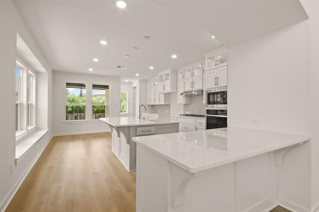 122 Canary Island Cir, Montgomery, TX 77316 - kitchen with wall oven, stainless steel microwave, gas stovetop, recessed lighting, and a kitchen island with sink