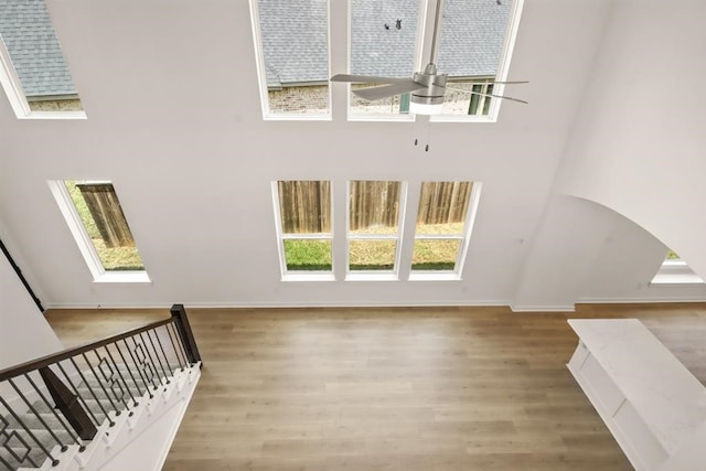 122 Canary Island Cir, Montgomery, TX 77316 - unfurnished living room with ceiling fan, healthy amount of natural light, a towering ceiling, wood finished floors, and a skylight