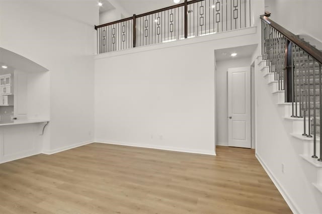 122 Canary Island Cir, Montgomery, TX 77316 - unfurnished living room with a high ceiling, wood finished floors, stairs, arched walkways, and baseboards